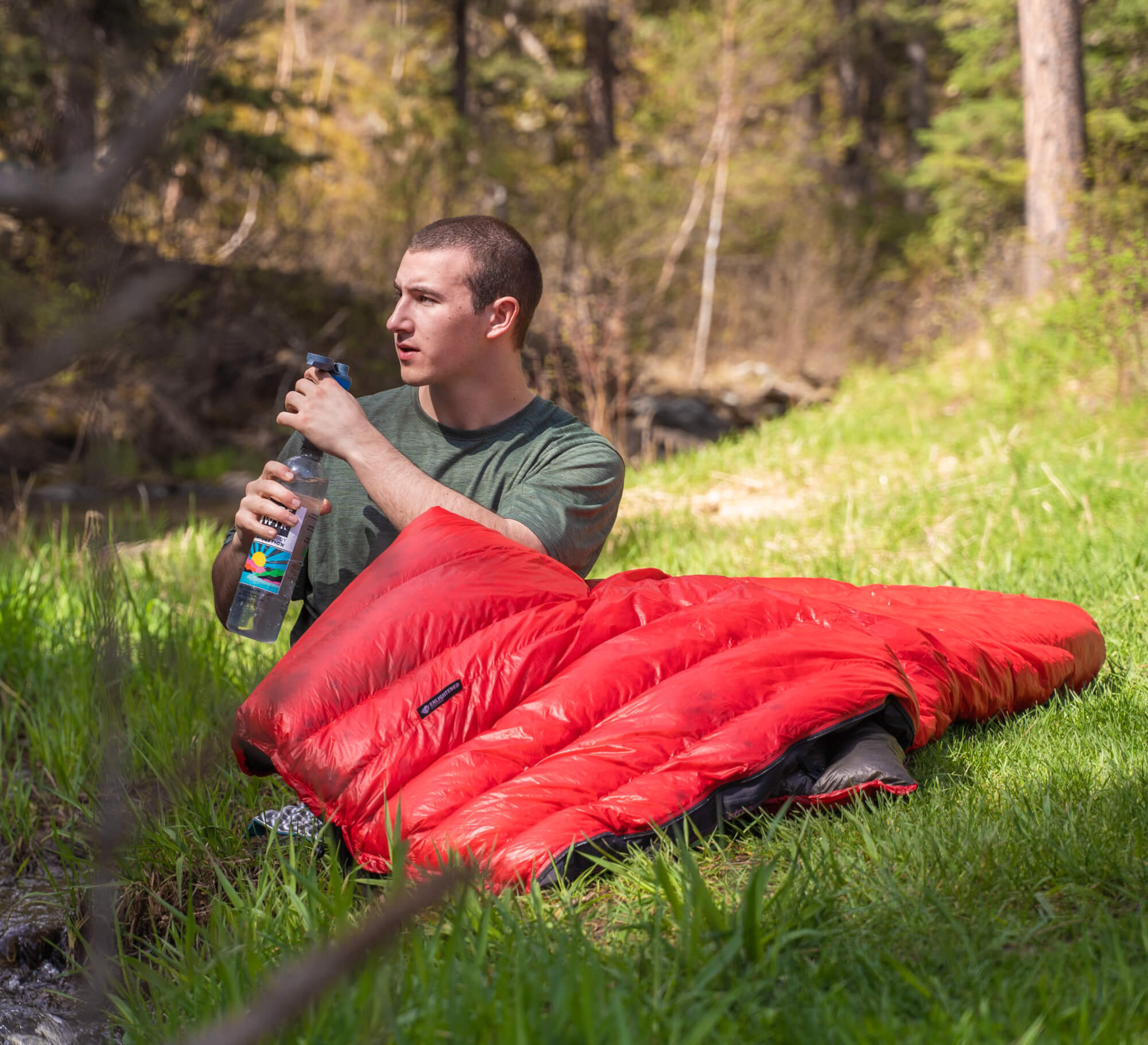 review image 1 -  someone drinking water with a quilt over their lap in the grass
