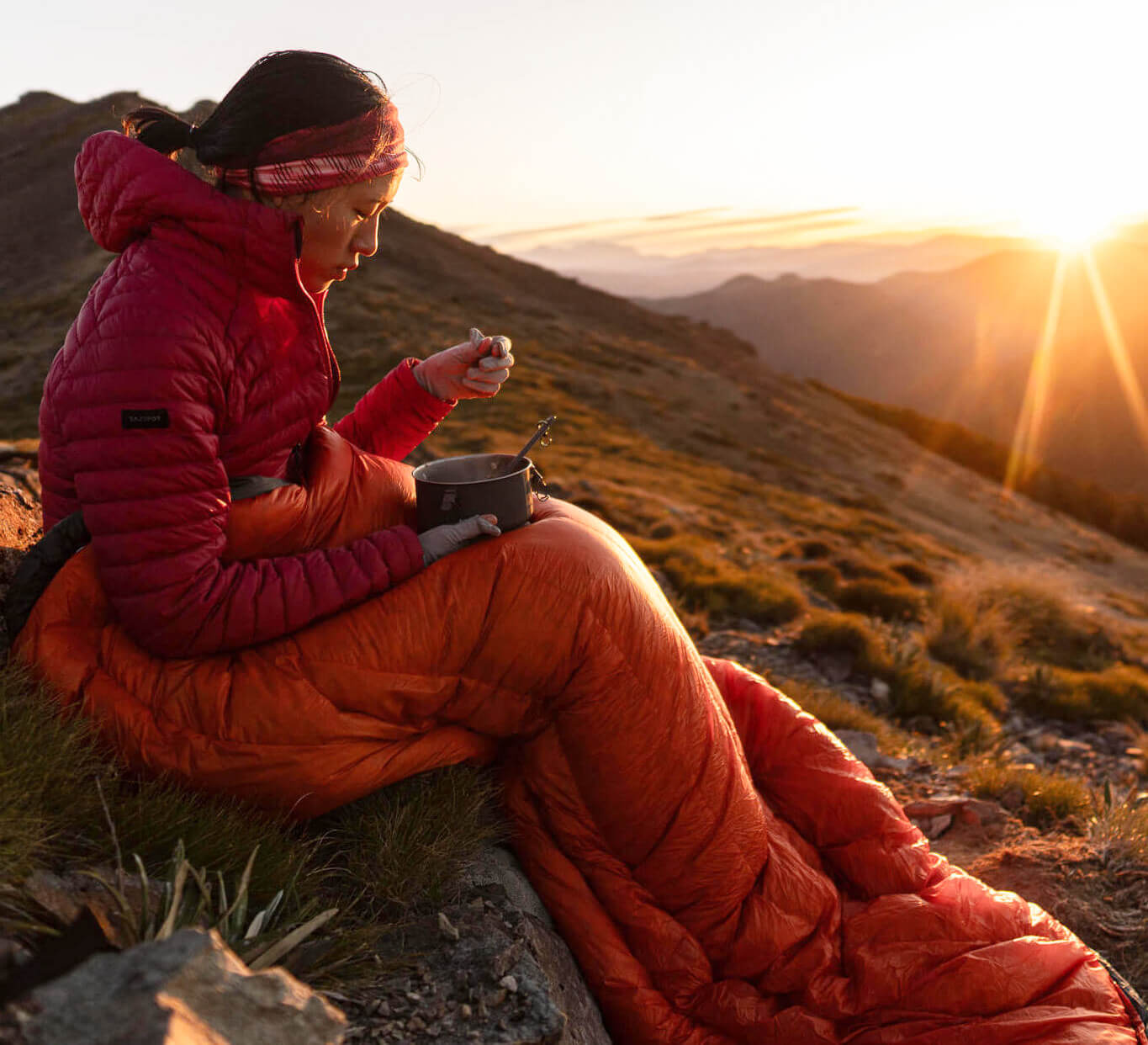 Sleeping Quilts - a girl sitting on a hill using a quilt as a blanket while she eats